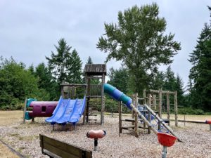 Playground featuring two wooden play structures, 4 slides, and several smaller play objects.